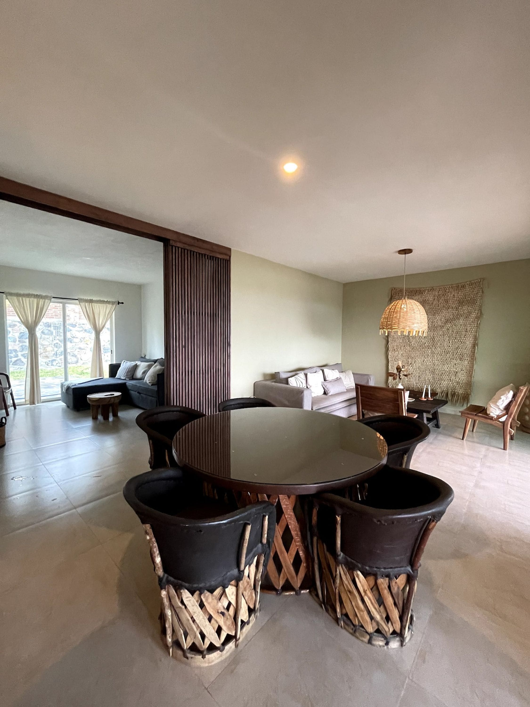 Un comedor con una mesa redonda y sillas, un sofá, y una lámpara colgante decorativa.