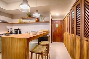 A modern kitchen with wooden cabinetry, a central island, and pendant lighting. - Estudio a 10 Pasos de la Playa Vallarta (Puerto Vallarta)