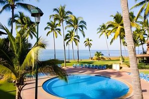 A swimming pool surrounded by palm trees and a view of the ocean. - Estudio a 10 Pasos de la Playa Vallarta (Puerto Vallarta)