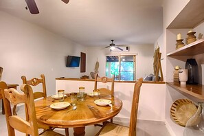 A dining area with a round wooden table, chairs, and a television mounted on the wall. - Estudio a 10 Pasos de la Playa Vallarta (Puerto Vallarta)