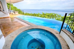 A swimming pool with a view of the sea, surrounded by a patio area with a hammock and outdoor furniture. - Amazing View to los Arcos -4 Bedroom Villa (Puerto Vallarta)