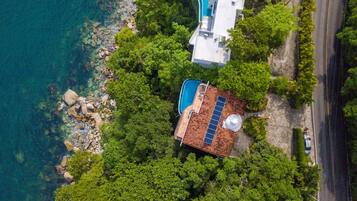 An aerial view of a property with a swimming pool, a separate pool area, and lush greenery.