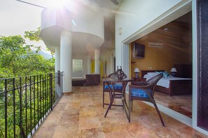 A balcony with a table and chairs, a sofa, and a bed with a TV. - Amazing View to los Arcos -4 Bedroom Villa (Puerto Vallarta)