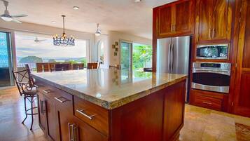 A modern kitchen with a large island, stainless steel appliances, and a view of the outdoors.