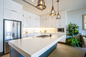 A modern kitchen with white cabinetry, stainless steel appliances, and pendant lighting.