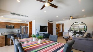 A modern kitchen with a microwave, refrigerator, and dining area with a colorful striped tablecloth.