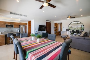 A modern kitchen with a microwave, refrigerator, and dining area with a colorful striped tablecloth.