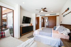 Een hotelkamer met een bed, een televisie, een plafondventilator en uitzicht op buiten.