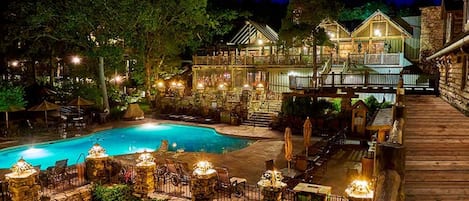 A pool area with a wooden deck, stone walls, and outdoor seating.