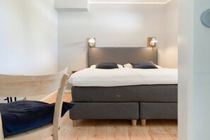 Ein Schlafzimmer mit einem Bett, Nachttischlampen, einem Sessel und Holzboden.
