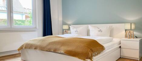 A bedroom with a bed, bedside tables, and a window.