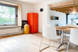 A modern kitchen with a large window, a red refrigerator, and a dining area with white chairs. - Holiday apartment with 2 bedrooms (Scharbeutz)
