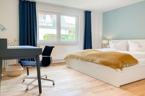 Une chambre d’hôtel avec un lit, un bureau, une chaise, une fenêtre et une vue sur l’extérieur.