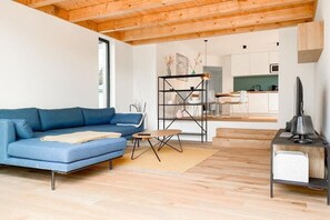 A modern living room with a blue sofa, a small coffee table, and a TV on a stand. - Holiday apartment with 2 bedrooms (Scharbeutz)