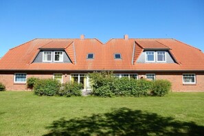 A two-story house with a sloped roof, a front entrance, and a well-maintained lawn. - Holiday apartment with 1 bedroom (Steinberg\/ OT Steinbergholz)