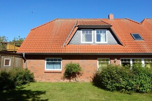 Een tweelaags huis met een rood pannendak, een klein dakraam en een gevel van baksteen.