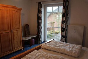 Een slaapkamer met een houten garderobe, een enkel bed, een stoel en een radiator.