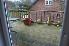 A wooden deck with a railing, a potted plant, and a play structure. - Holiday apartment with 1 bedroom (Steinberg\/ OT Steinbergholz)