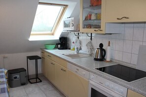 Eine kompakte Küche mit Fenster, Mikrowelle, Spüle und Herd.
