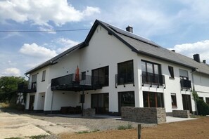 Ein modernes, zweistöckiges Haus mit Balkon, großen Fenstern und einem Steinfundament.