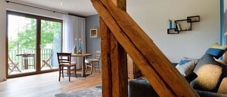 Une pièce dotée d’une structure en poutres apparentes, d’un coin repas avec des chaises et une table, et d’un canapé agrémenté de coussins.