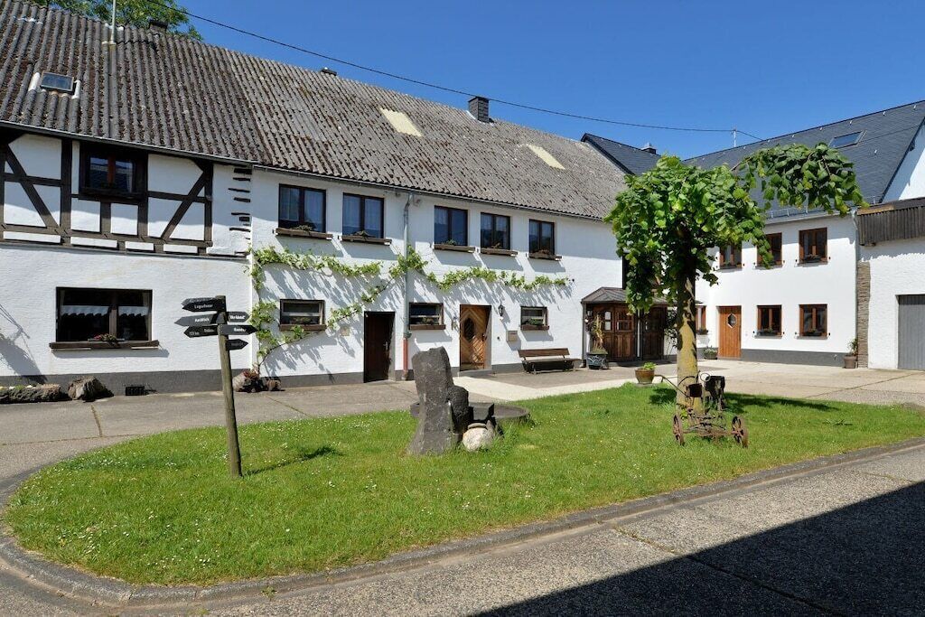 Un bâtiment traditionnel, avec un panneau indicateur, une structure en pierre et un arbre au premier plan.