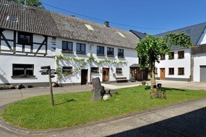 Ein traditionelles Gebäude mit Wegweiser, Steinmauer und Baum im Vordergrund.