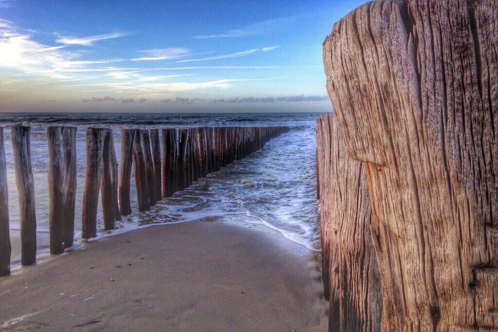 A wooden pier extending into the sea with waves gently lapping at its base.