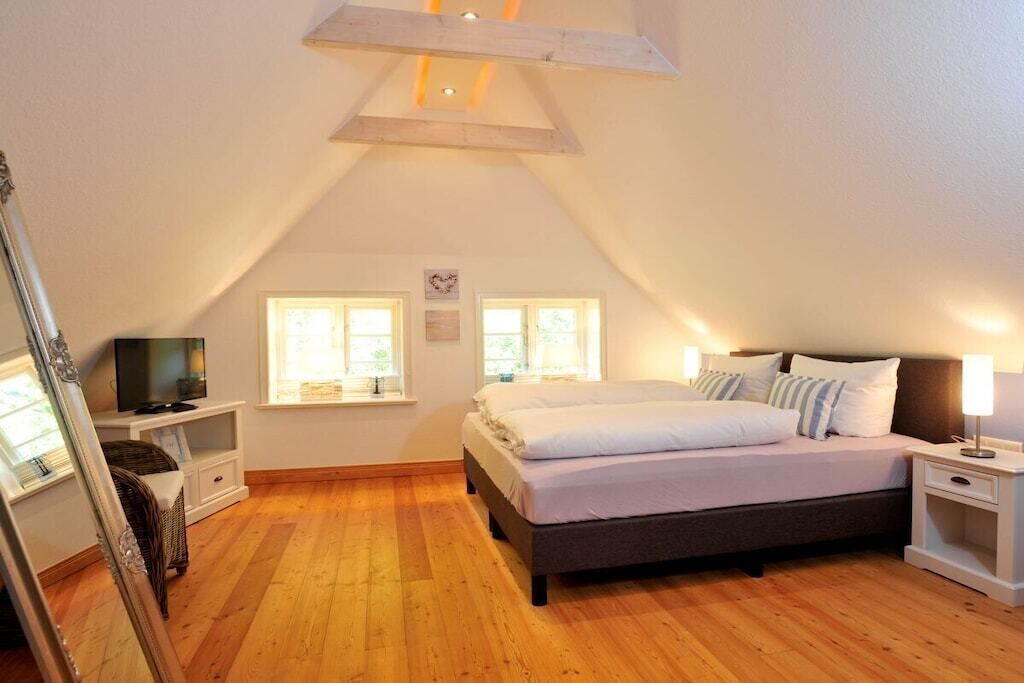 A bedroom with a bed, bedside tables, a television, and a window.