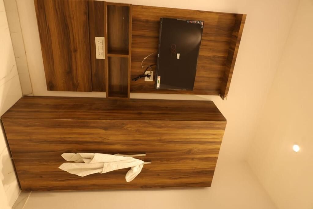 A wooden vanity with a mirror and a power outlet.