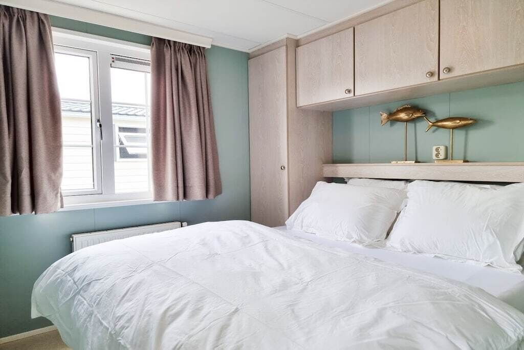 A bedroom with a bed, a window with curtains, and a wooden headboard with fish decorations.