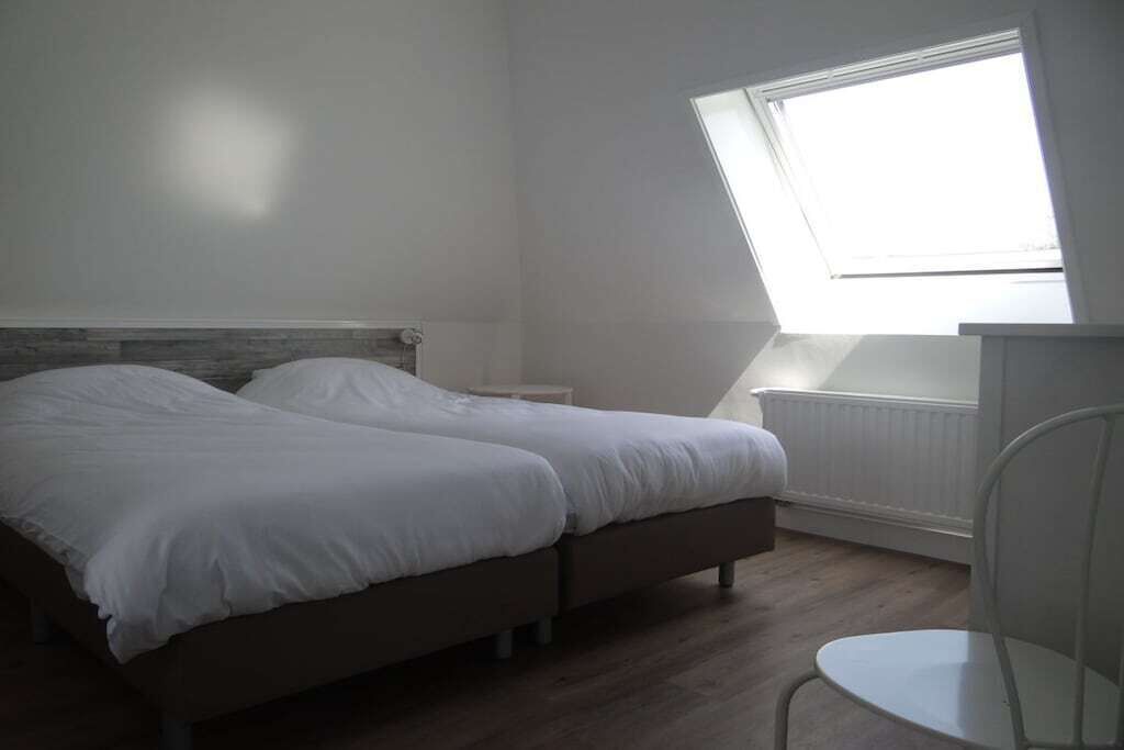 A bedroom with two beds, a window, and a radiator.