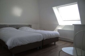 A bedroom with two beds, a window, and a radiator. - Apartment in Oostkapelle with swimming pool (oostkapelle)