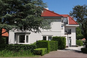A two-story house with a red-tiled roof, white exterior walls, and a front entrance with a small porch. - Apartment in Oostkapelle with swimming pool (oostkapelle)