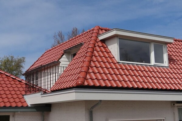 A residential building with a red-tiled roof, a dormer window, and a visible chimney. - Apartment in Oostkapelle with swimming pool (oostkapelle)