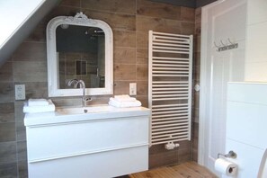A bathroom with a white vanity, a mirror, a towel rack, and a towel warmer. - Apartment in Oostkapelle with swimming pool (oostkapelle)