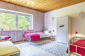 A bedroom with a bed, bedside table, wardrobe, window, and a view of greenery outside. - Natur&Strand Vacation Rental (Flensburg)
