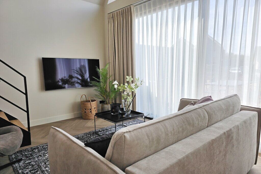 Uma sala de estar com sofá, televisão de tela plana, mesa de centro e um vaso com planta.
