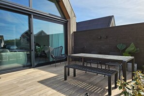 An outdoor patio with a wooden deck, a table, and chairs. - Holiday apartment with 1 bedroom (Domburg)