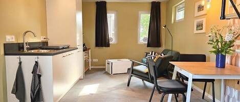 Een knus woongedeelte met een kitchenette, eethoek en een bank.