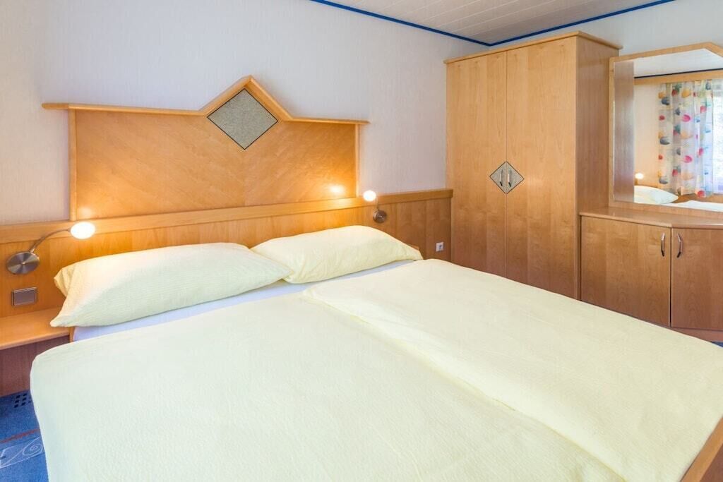 Una habitació d'hotel amb llit, làmpades de nit, un armari i un mirall.
