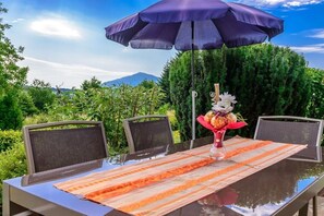 Ein Essbereich im Freien mit Tisch, Stühlen und einem großen Sonnenschirm.