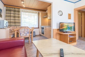 Ein gemütlicher Wohnbereich mit Sofa, Esstisch, Fernseher und Küchenzeile.