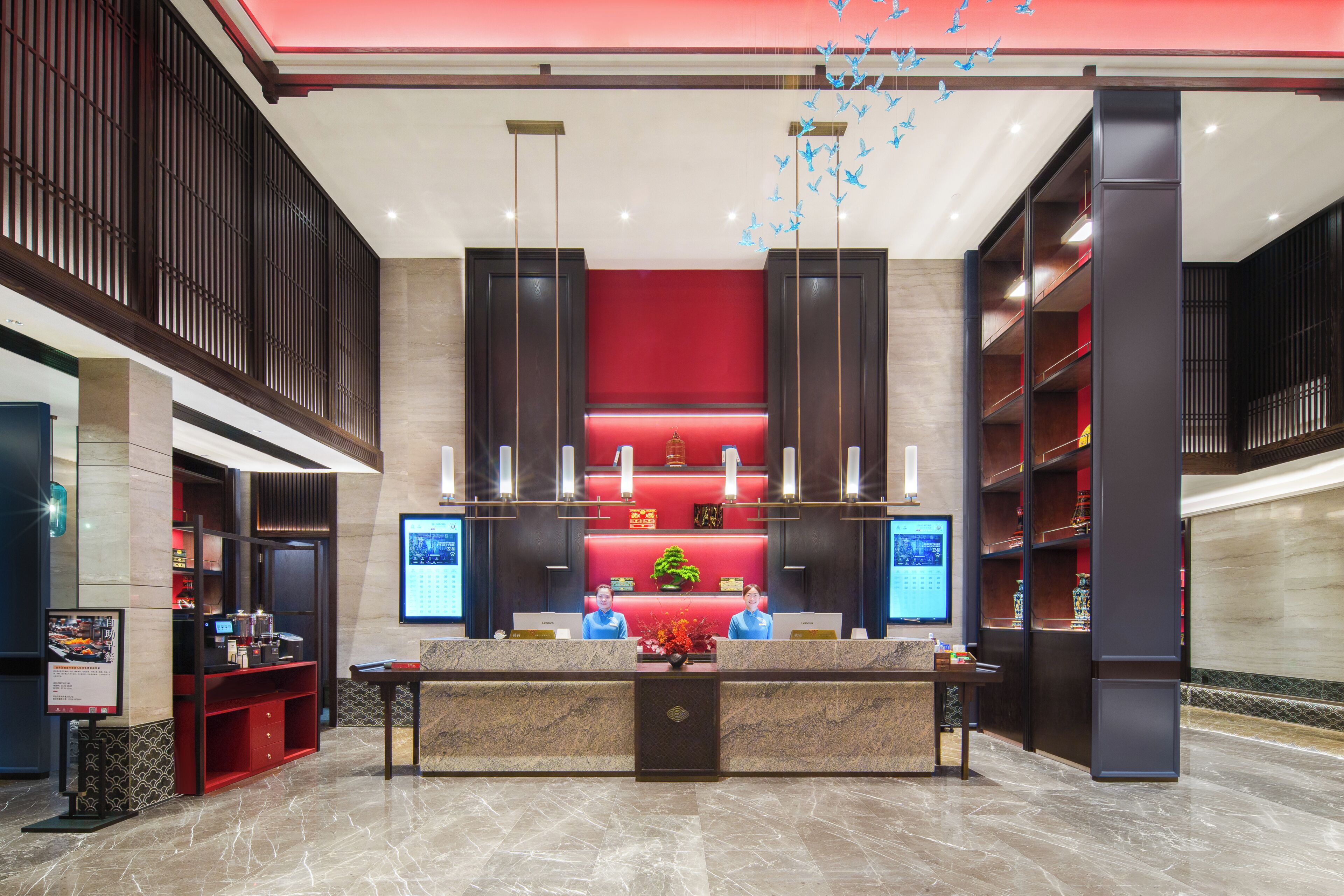 A hotel reception area with a marble floor, a reception desk, and a red accent wall.