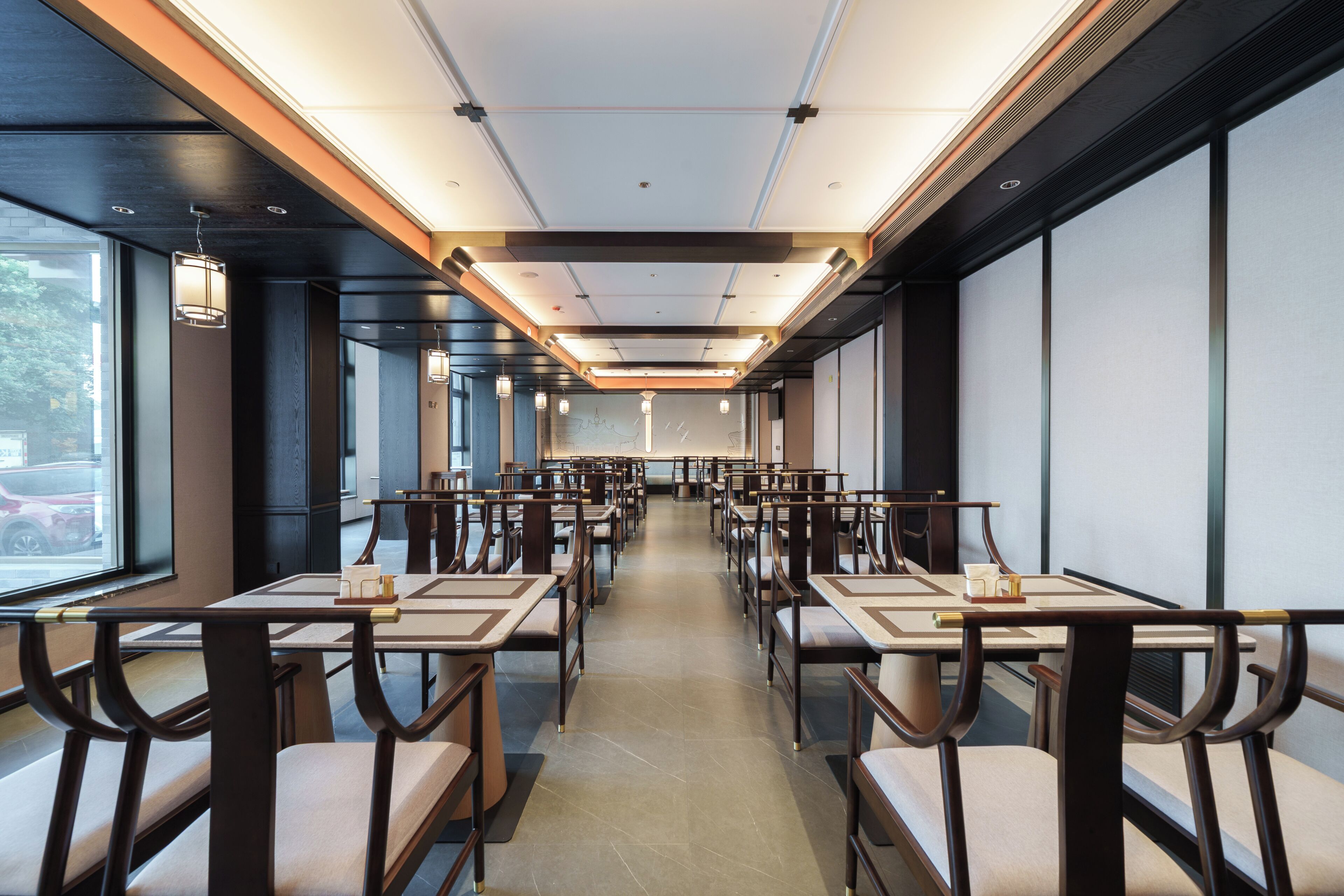 Un restaurante con mesas largas, iluminación moderna y amplios ventanales.
