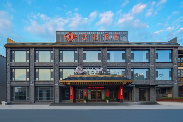 Un hotel moderno con un letrero llamativo y una entrada tradicional.