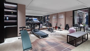A modern gym with various exercise equipment, a bench, and a massage table.