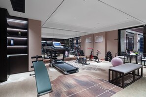 A modern gym with various exercise equipment, a bench, and a massage table.