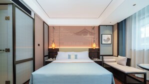Una habitación de hotel con una cama grande, mesitas de noche, un escritorio, una silla y vistas a un edificio tradicional.