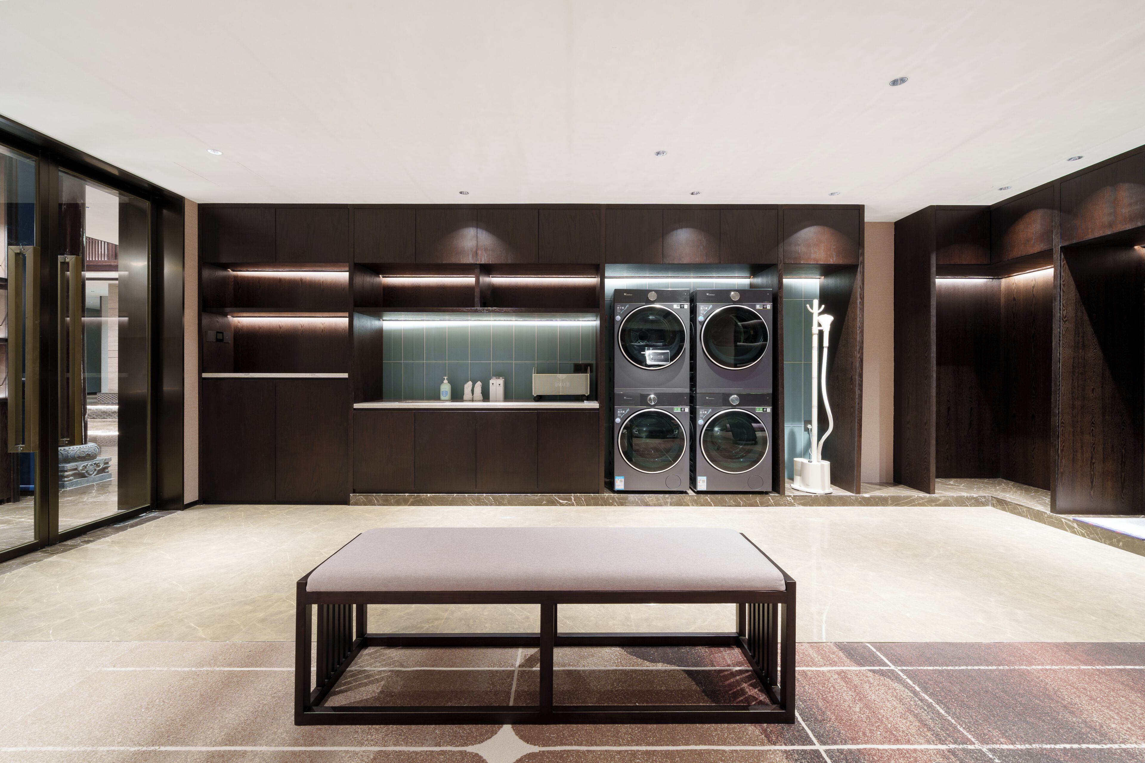 A modern kitchen with built-in appliances, a marble countertop, and a bench.